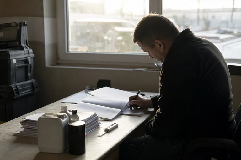 Bauleiter plant Gefahrstofftermine in einem Kalender neben Sicherheitsdatenblättern