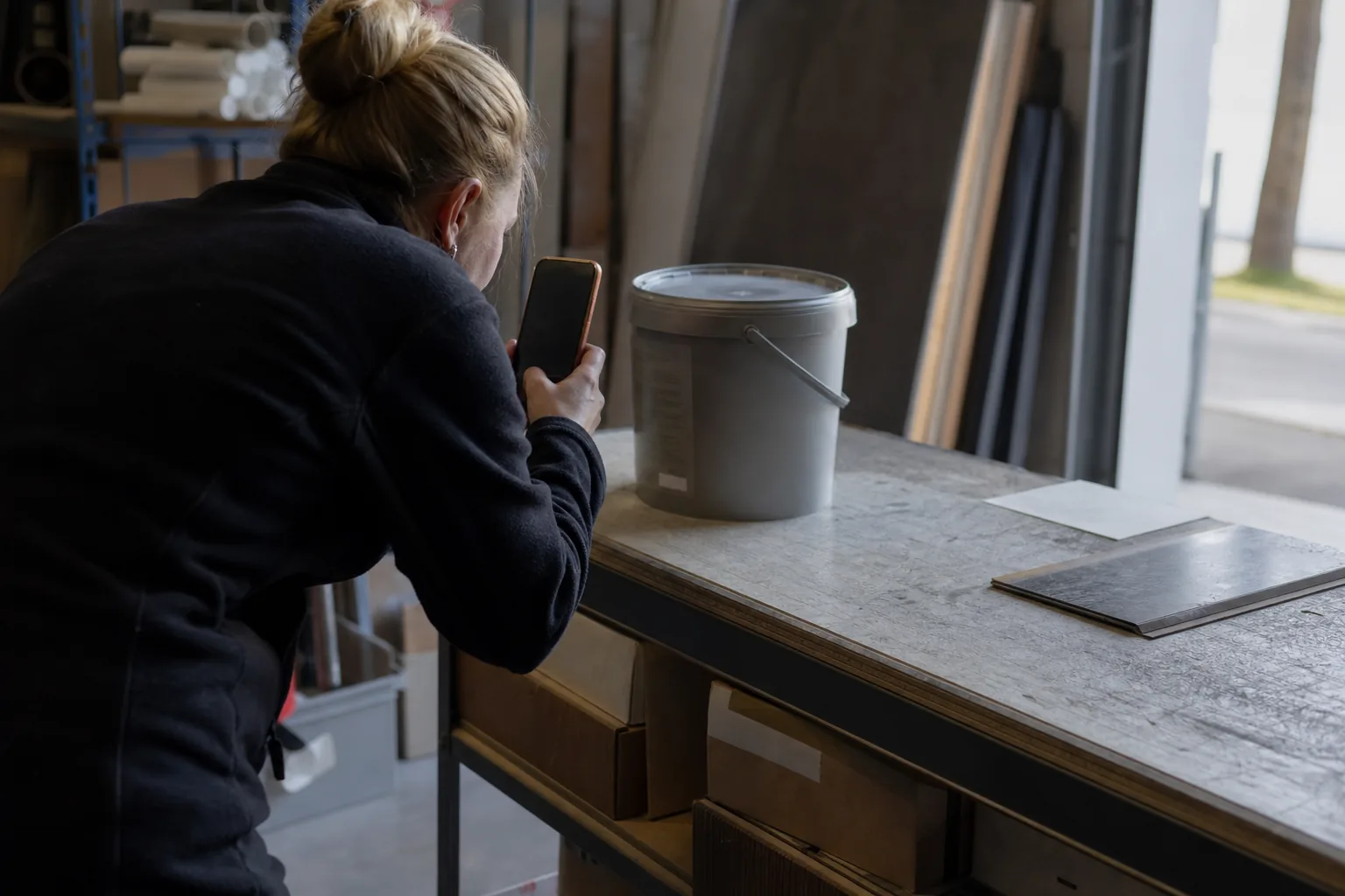 Bodenlegerin erfasst ein Klebstoffgebinde im Materiallager